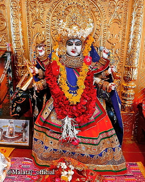 Ornate Malataj Maa Deity Idol Adorned With Red And Yellow Flower Garlands In Temple Setting HD phone wallpaper