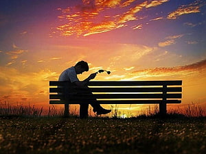 Silhouette of a man sitting alone on a park bench holding headphones against a vibrant sunset sky, : Alone, sad boy alone HD wallpaper