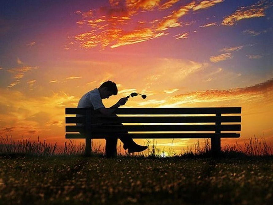 Silhouette of a man sitting alone on a park bench holding headphones against a vibrant sunset sky, : Alone, sad boy alone HD wallpaper