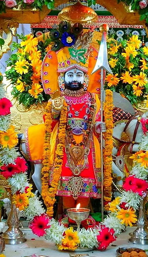 Vibrant Khatu Shyam Ji Temple Idol Surrounded by Marigold Garlands and Flowers HD phone wallpaper
