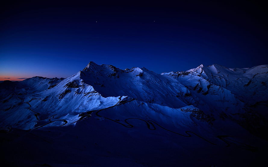 Snowy Mountain Peaks at Twilight with Winding Road and Deep Blue Sky HD wallpaper