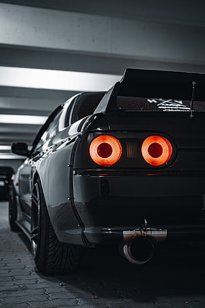 Rear View of a Black Nissan GTR R32 with Glowing Circular Taillights and Large Rear Spoiler HD phone wallpaper