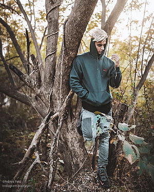Danish Zehen in a forest setting wearing a dark hoodie and distressed jeans HD phone wallpaper