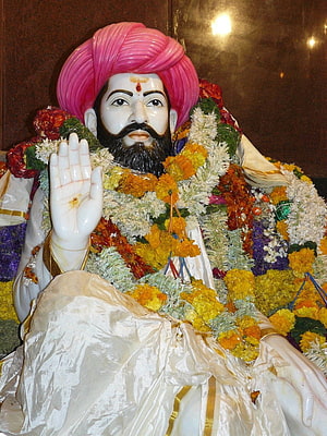 Sant Sevalal Maharaj Statue Adorned With Marigold Garlands And Pink Turban HD phone wallpaper