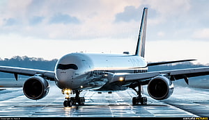 Airbus A350-900 XWB aircraft taxiing on a wet runway with landing lights illuminated HD wallpaper