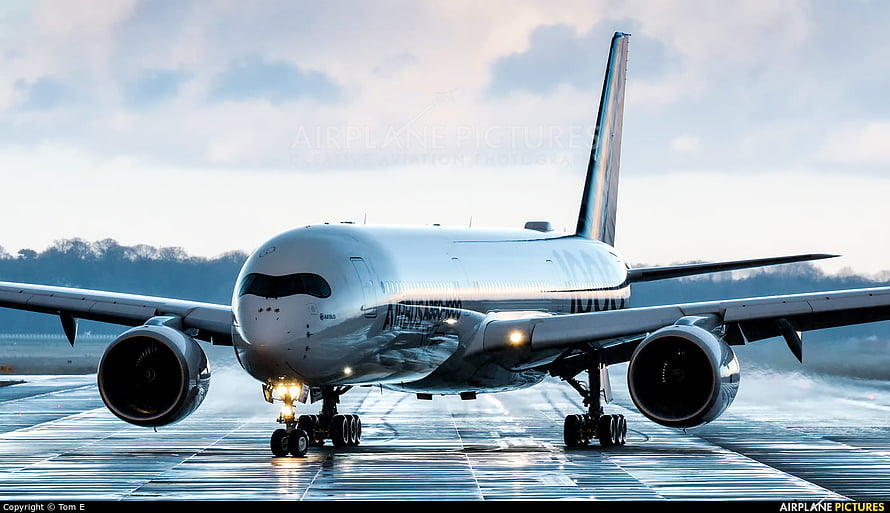 Airbus A350-900 XWB aircraft taxiing on a wet runway with landing lights illuminated HD wallpaper