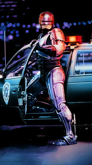 RoboCop Standing Beside a Detroit Police Cruiser in a Neon-Lit Night Scene HD phone wallpaper