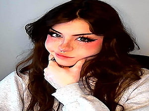 Portrait of a girl with long dark hair, freckles, and a nose ring, wearing a white sweater and resting her chin on her hand HD wallpaper