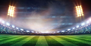 Empty Football Stadium at Night with Bright Floodlights and Green Grass Field HD wallpaper