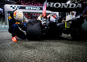 Max Verstappen Crouches Beside Red Bull Racing Honda Formula 1 Car On Wet Night Circuit HD wallpaper