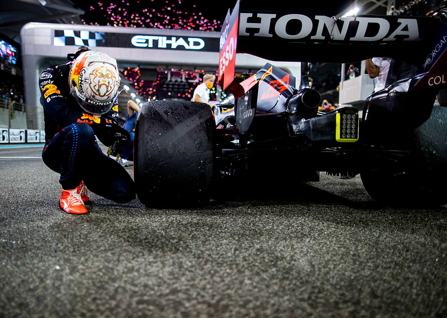 Max Verstappen Crouches Beside Red Bull Racing Honda Formula 1 Car On Wet Night Circuit HD wallpaper