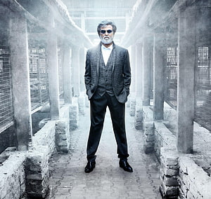 Rajinikanth in a grey three-piece suit and sunglasses standing in a foggy industrial corridor from the film Kabali HD wallpaper