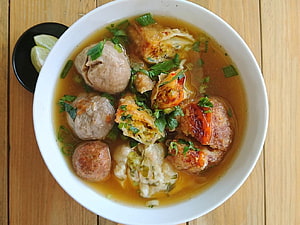 Indonesian Bakso Meatball Soup with Fried Tofu and Fresh Herbs in a White Bowl HD wallpaper