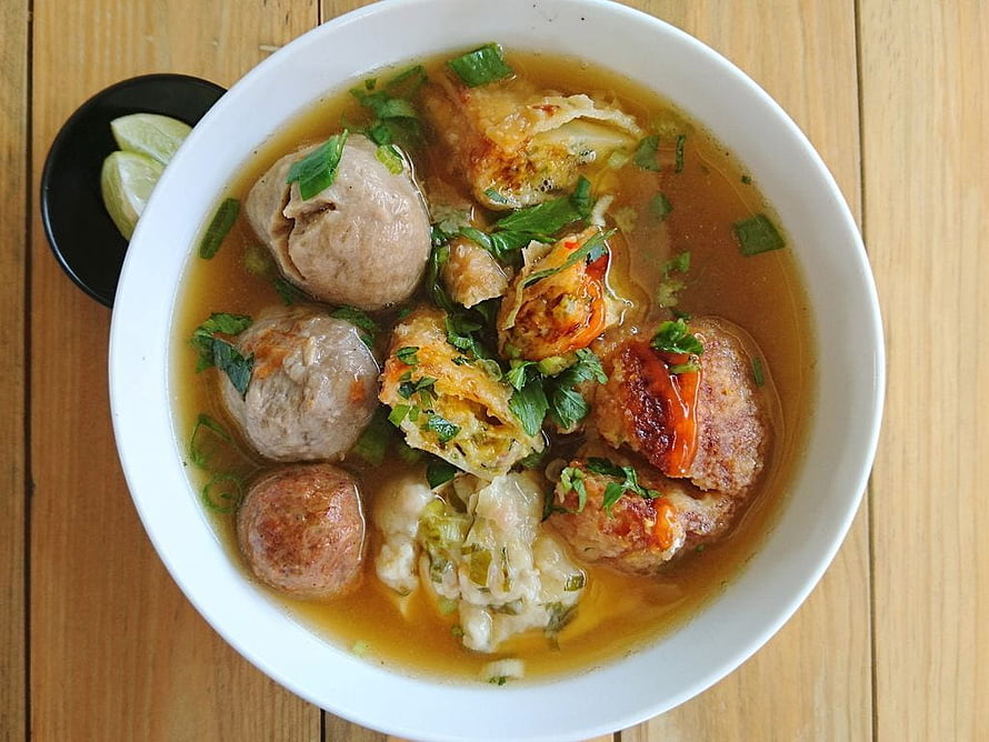 Indonesian Bakso Meatball Soup with Fried Tofu and Fresh Herbs in a White Bowl HD wallpaper