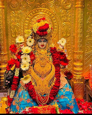 Goddess Kali adorned in gold jewelry and red flowers against an ornate golden temple background HD phone wallpaper