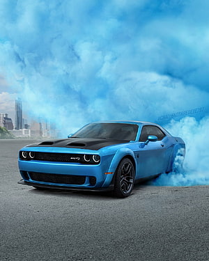 Blue Dodge Challenger SRT Hellcat performing a burnout with blue smoke against a city skyline HD phone wallpaper