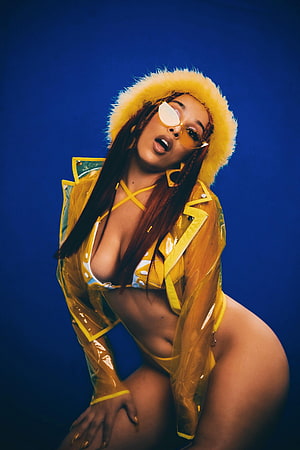 Doja Cat in Yellow Raincoat and Fur Hat Against Blue Background HD phone wallpaper