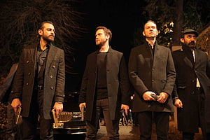 Four armed men in dark coats standing at night in a tense crime scene HD wallpaper
