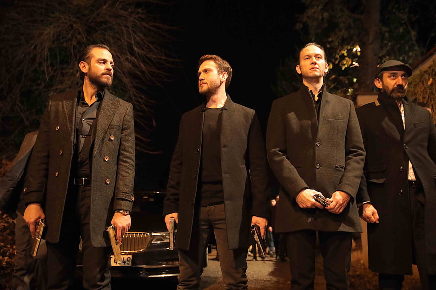 Four armed men in dark coats standing at night in a tense crime scene HD wallpaper