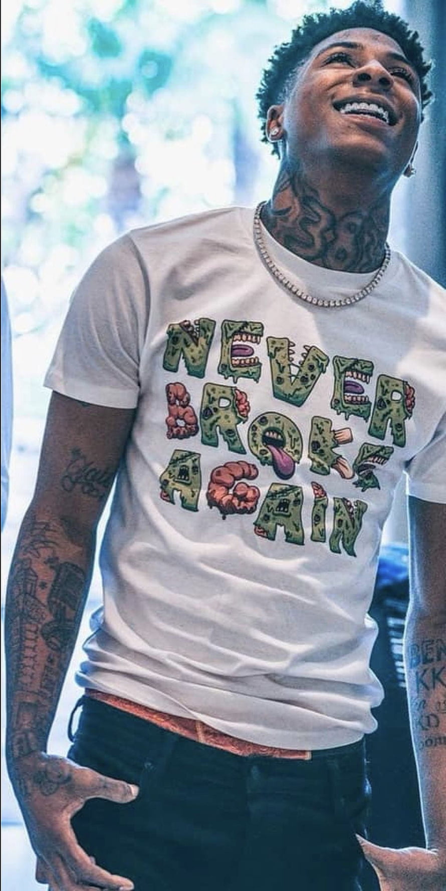 NBA Youngboy smiling in white graphic t-shirt with visible tattoos and diamond chain HD phone wallpaper