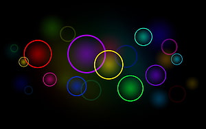 Vibrant multicolored neon circles floating on a dark abstract background HD wallpaper