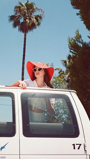 Lana Del Rey in a red sun hat leaning from a white van under a palm tree HD phone wallpaper
