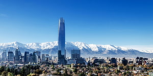Santiago de Chile skyline with the iconic Torre KIO and snow-capped Andes mountains under a clear blue sky HD wallpaper