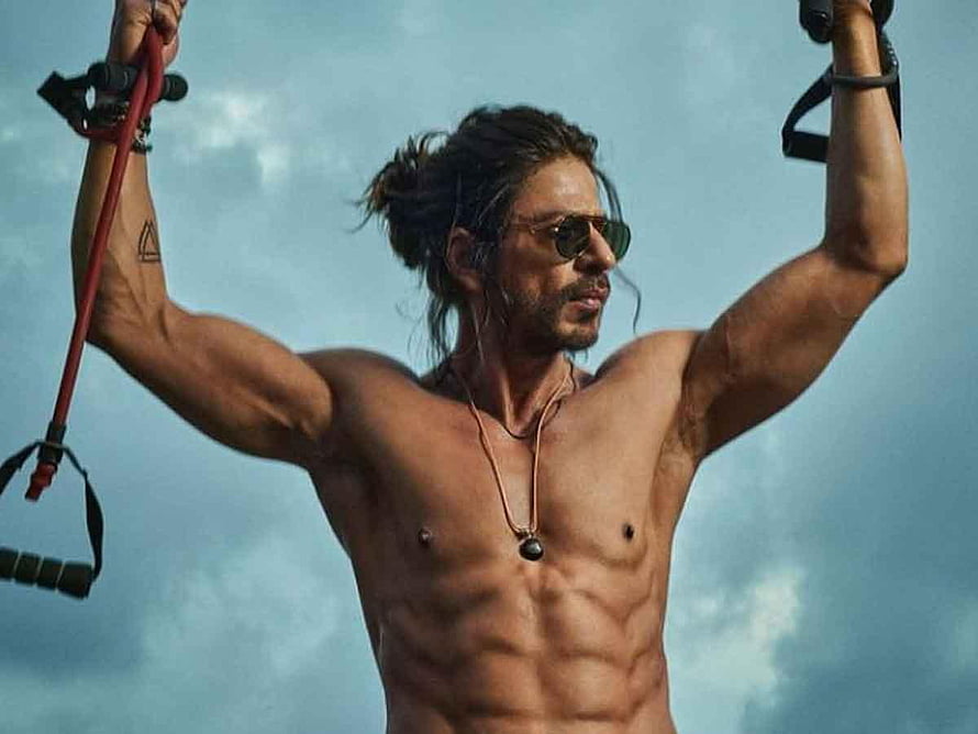 Shah Rukh Khan as Pathaan in a shirtless action pose with resistance bands against a cloudy sky HD wallpaper