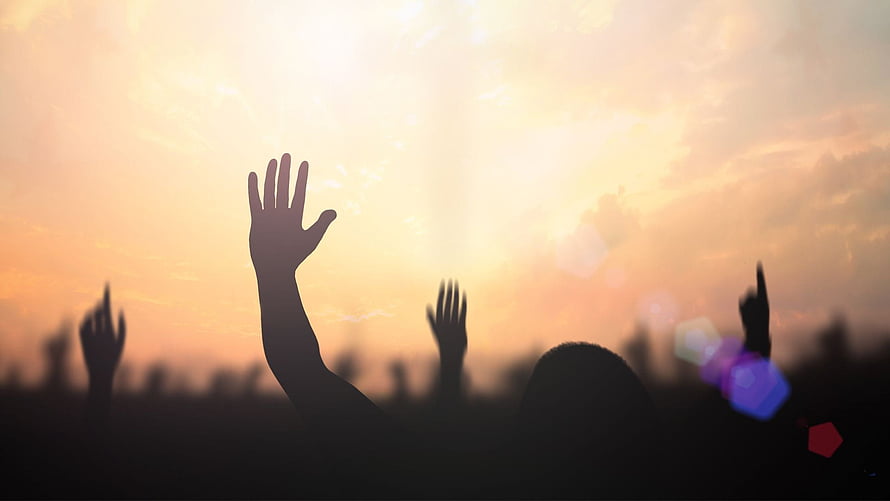 Silhouetted hands raised in worship against a golden sunset sky with lens flare HD wallpaper