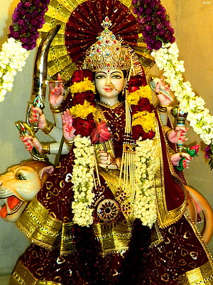 Goddess Durga Matha adorned in maroon and gold with a tiger mount and floral garlands HD phone wallpaper