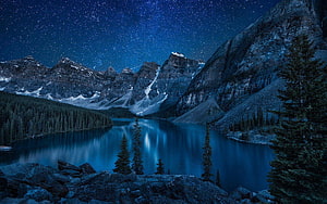Starry Night Sky Over a Serene Mountain Lake with Snow-Capped Peaks and Pine Trees HD wallpaper