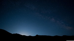 Milky Way Galaxy Arching Over Dark Mountain Silhouette at Night HD wallpaper