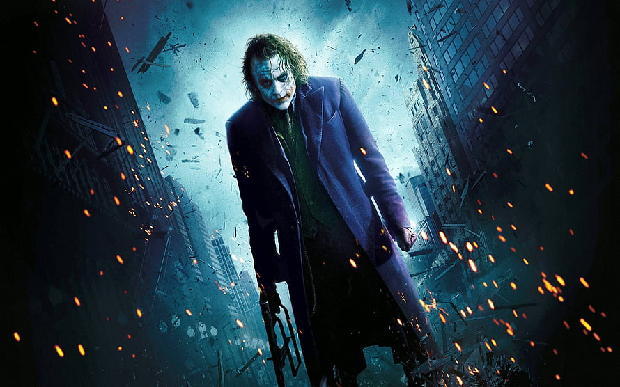 The Joker from The Dark Knight standing amidst city destruction and flying sparks HD wallpaper