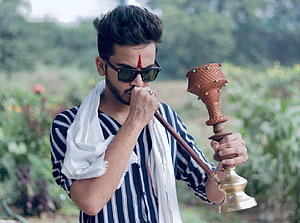 Elvish Yadav smoking hookah outdoors in striped shirt and sunglasses HD wallpaper