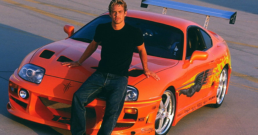 Paul Walker as Brian O'Conner leaning on the iconic orange Toyota Supra from The Fast and the Furious movie franchise HD wallpaper