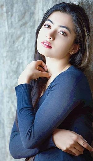 Portrait of a woman with long dark hair wearing a blue sweater posing against a textured wall, Rashmika mandanna by sarushivaanjali, rashmika mandanna HD phone wallpaper