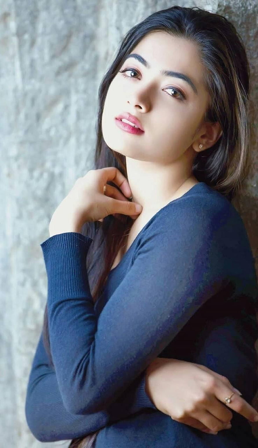Portrait of a woman with long dark hair wearing a blue sweater posing against a textured wall, Rashmika mandanna by sarushivaanjali, rashmika mandanna HD phone wallpaper