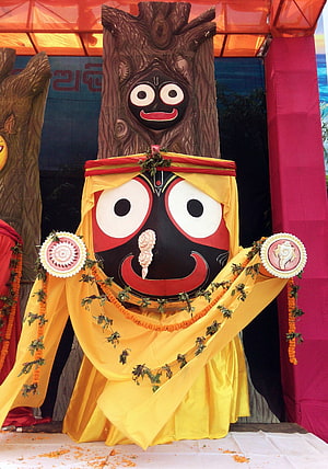 Jagannath deity statue adorned in yellow silk with marigold garlands and traditional ornaments HD phone wallpaper