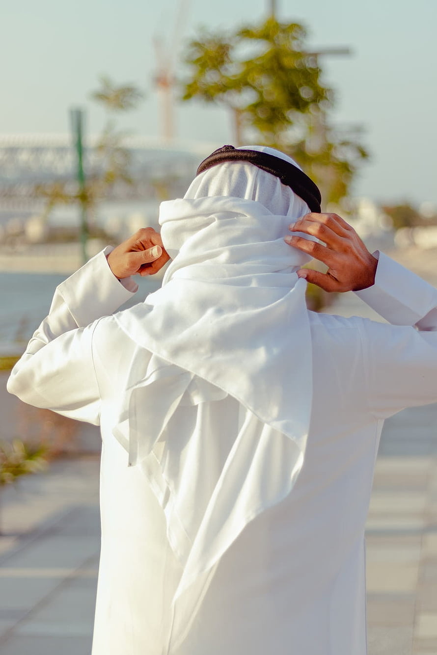 Arab man adjusting traditional white thobe and ghutra headwear outdoors, 100 Arab Man, arab boy HD phone wallpaper
