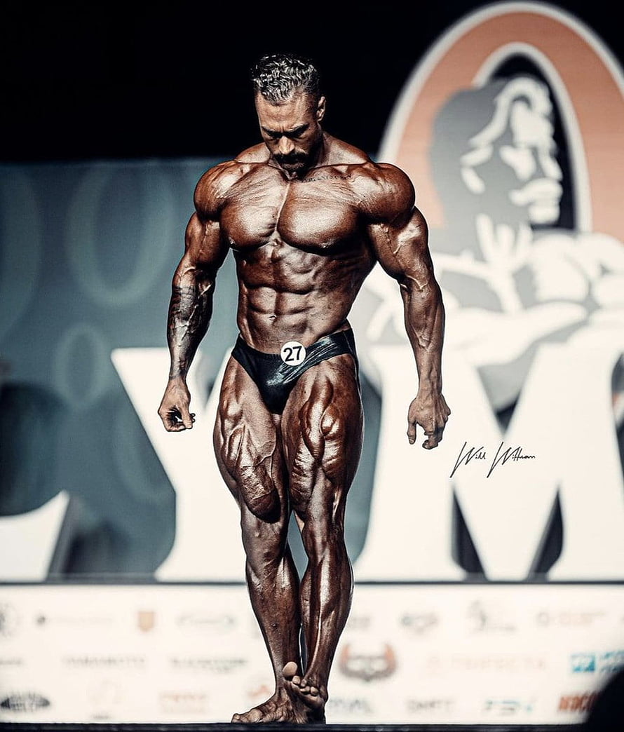 Professional Bodybuilder Posing On Stage With Extreme Muscle Definition And Dark Tan HD phone wallpaper