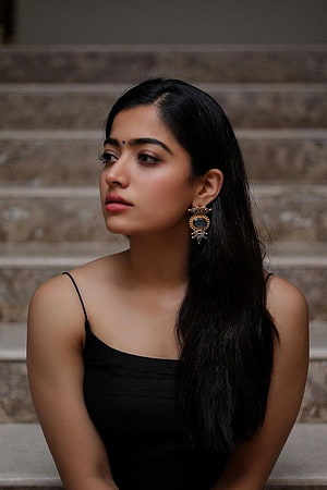 Rashmika Mandanna Portrait in Black Dress with Ornate Earrings on Stone Steps HD phone wallpaper