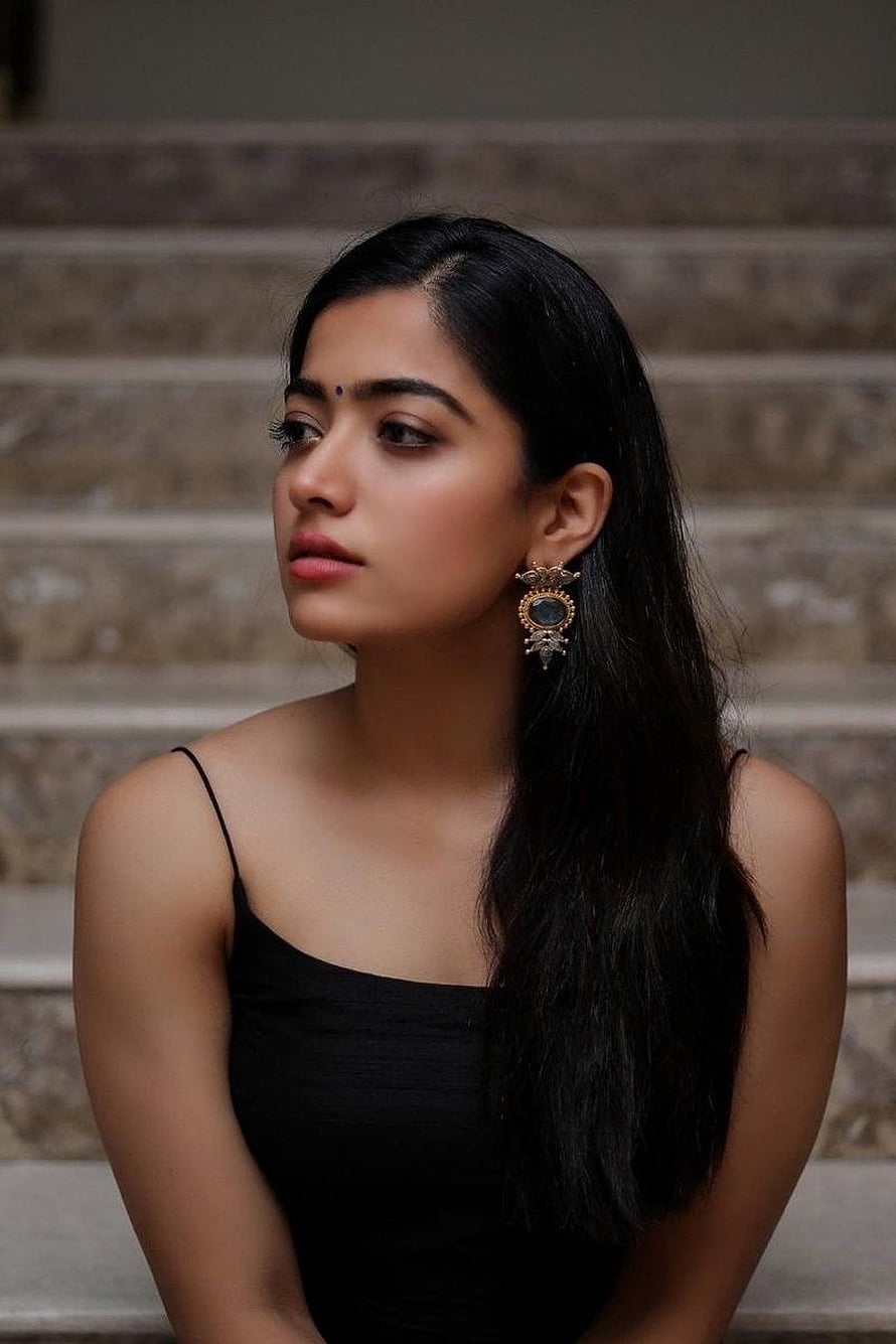 Rashmika Mandanna Portrait in Black Dress with Ornate Earrings on Stone Steps HD phone wallpaper