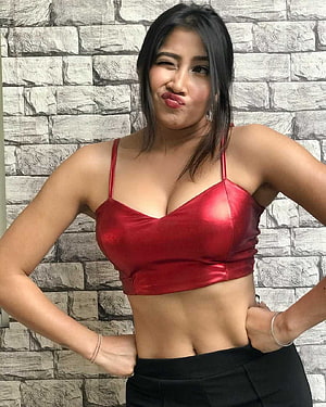 Sofia Ansari posing in a red satin crop top against a textured stone wall HD phone wallpaper