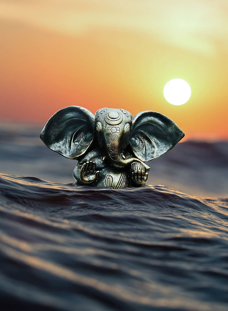 Ganesha Bronze Statue Emerging From Ocean Waves At Golden Sunset HD phone wallpaper