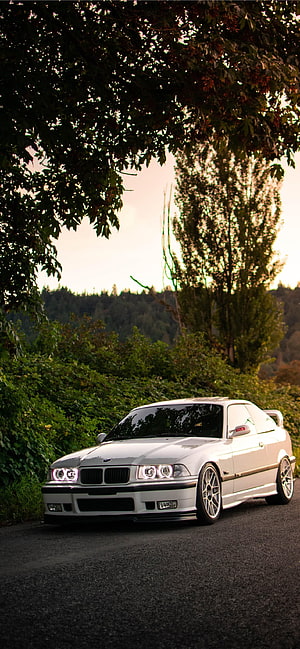 White BMW E36 Coupe Parked on a Scenic Forest Road at Sunset HD phone wallpaper