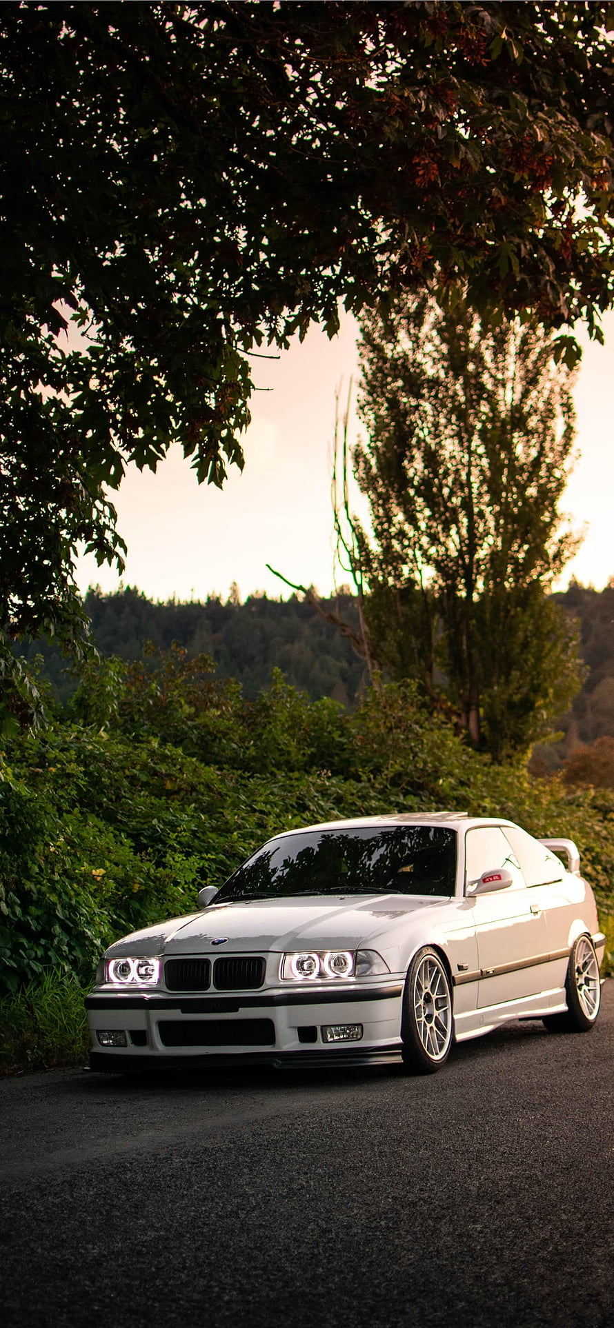 White BMW E36 Coupe Parked on a Scenic Forest Road at Sunset HD phone wallpaper