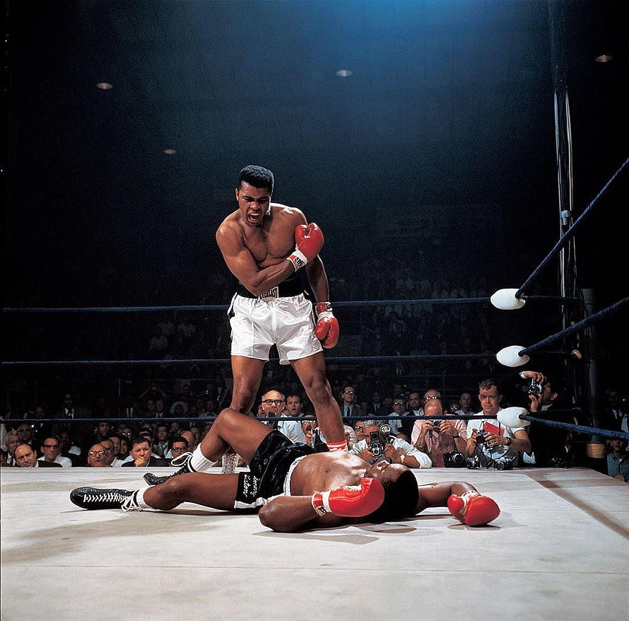 Muhammad Ali Standing Over Fallen Opponent in Boxing Ring HD wallpaper