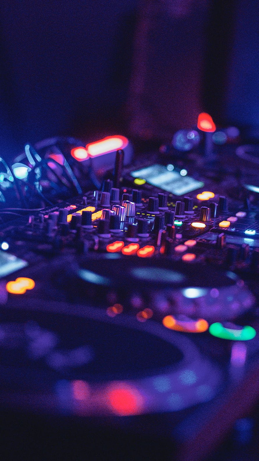 Neon-lit DJ mixer with glowing knobs and illuminated buttons in a dark club setting HD phone wallpaper