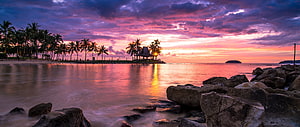 Vibrant Pink and Purple Sunset Over Tropical Beach with Palm Trees and Rocks HD wallpaper