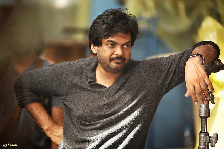 Puri Jagannadh in a casual grey henley shirt leaning on a camera tripod HD wallpaper